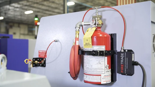 Firetrace Löschanlage an einer Industriemaschine installiert, mit rotem Detektionsschlauch und Steuermodul